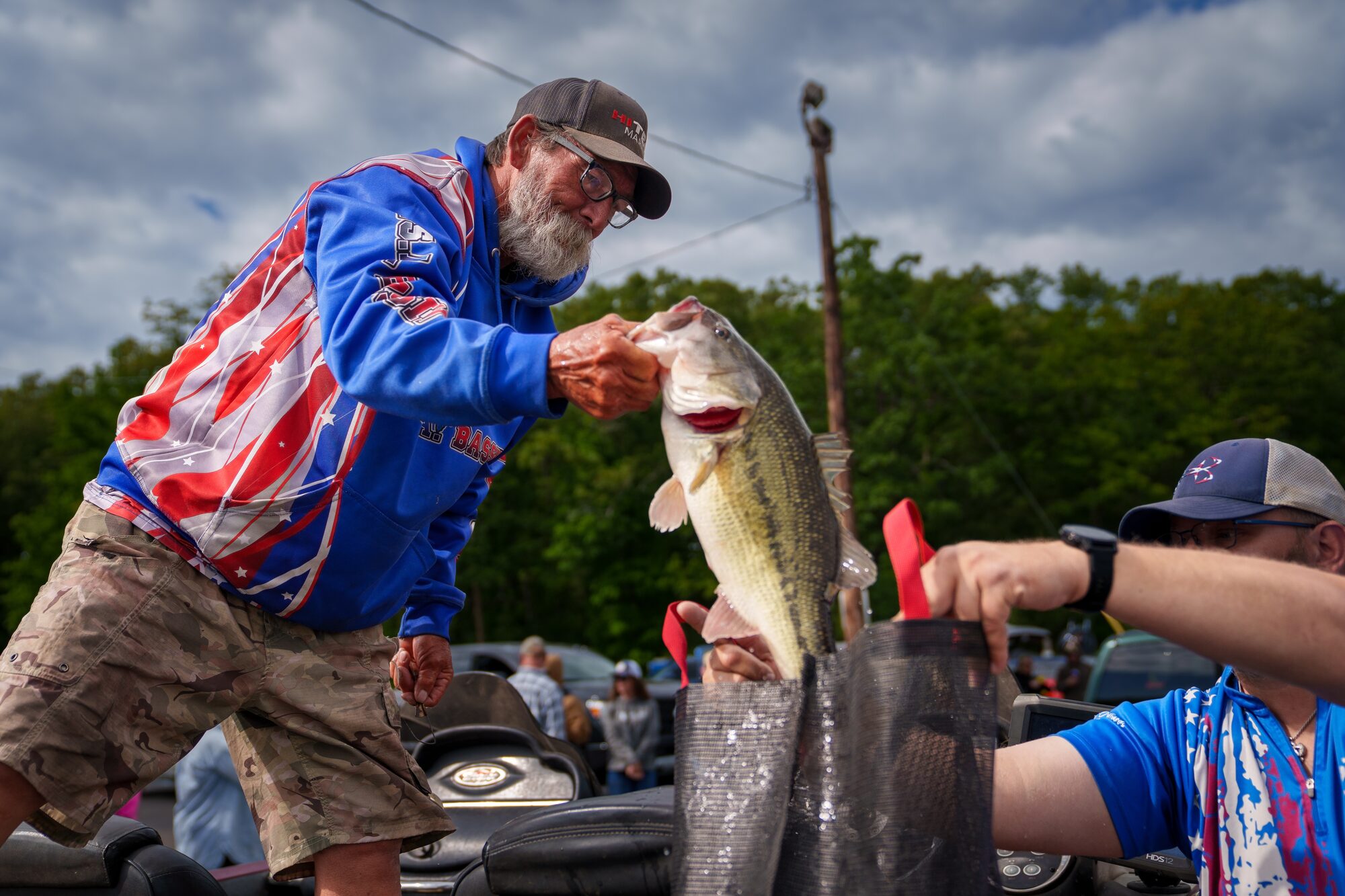 Angler placing a bass into a weigh-in bag during a USA BASSIN event